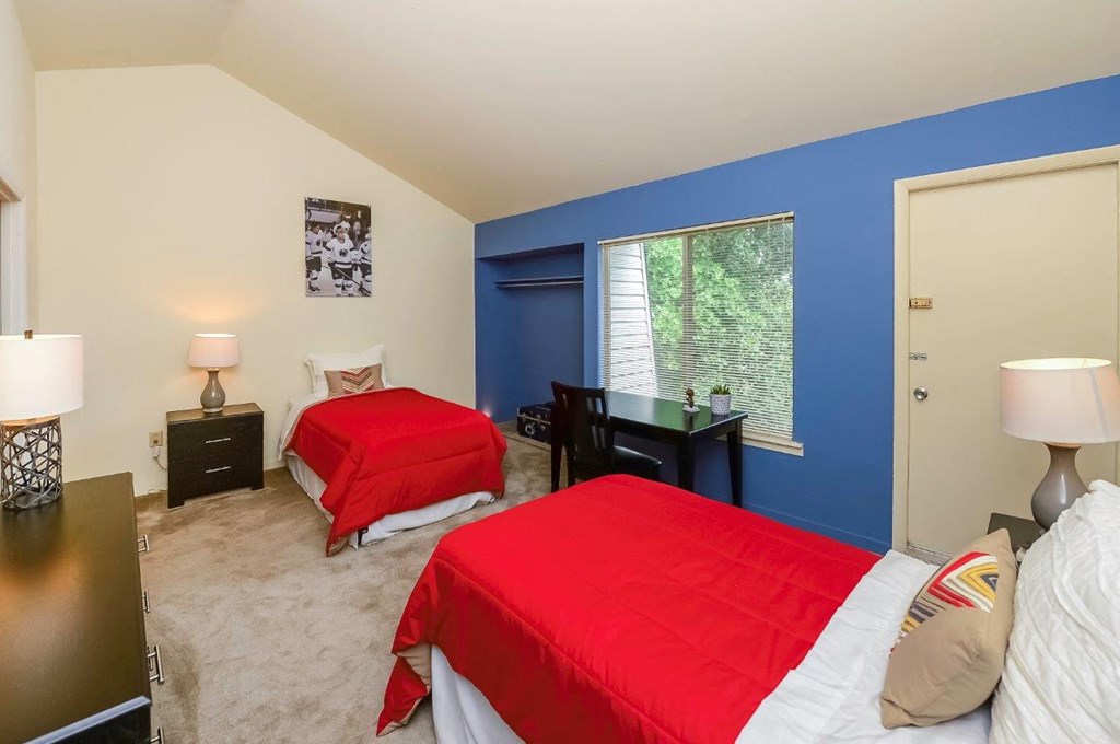 a bedroom with two beds and a desk and a window