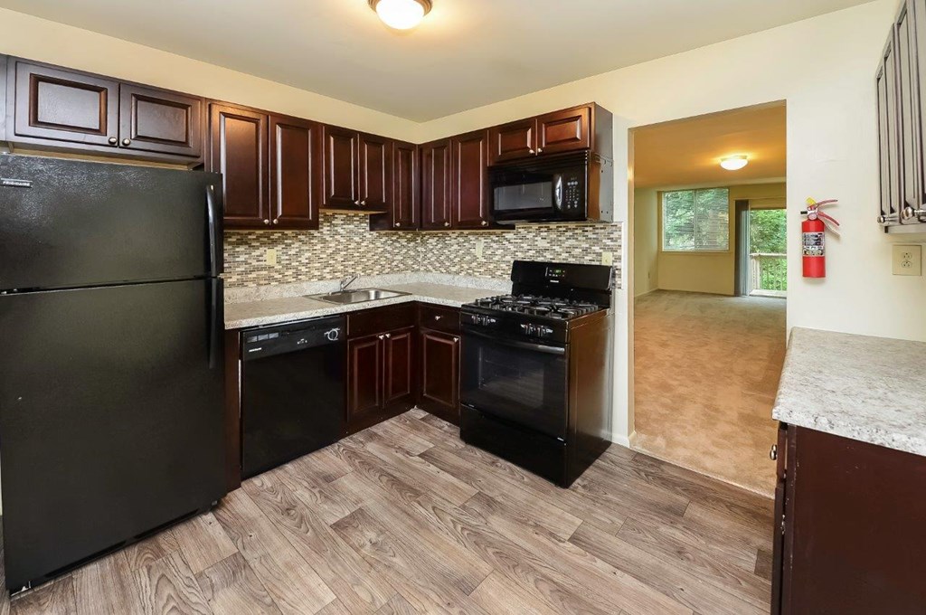 a kitchen with black appliances and wooden floors