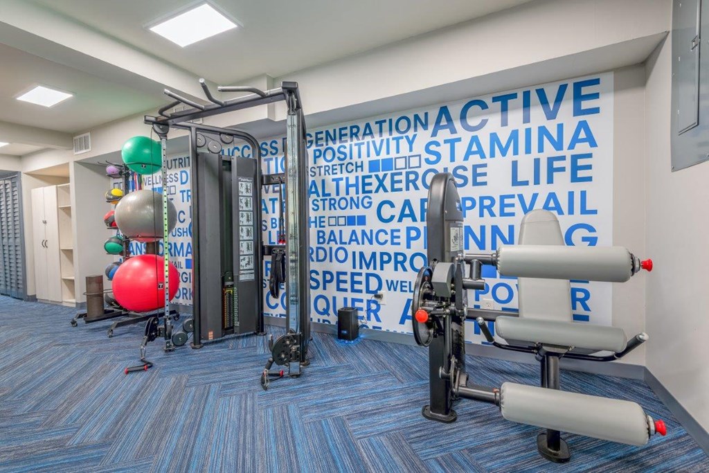 a workout room with weights and a wall covered in words