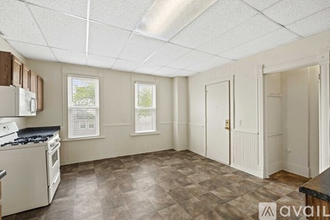 A kitchen with a white stove top oven and a tiled floor.