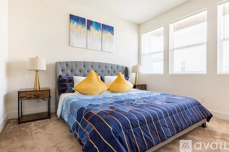 A bedroom with a blue bedspread and a grey headboard.