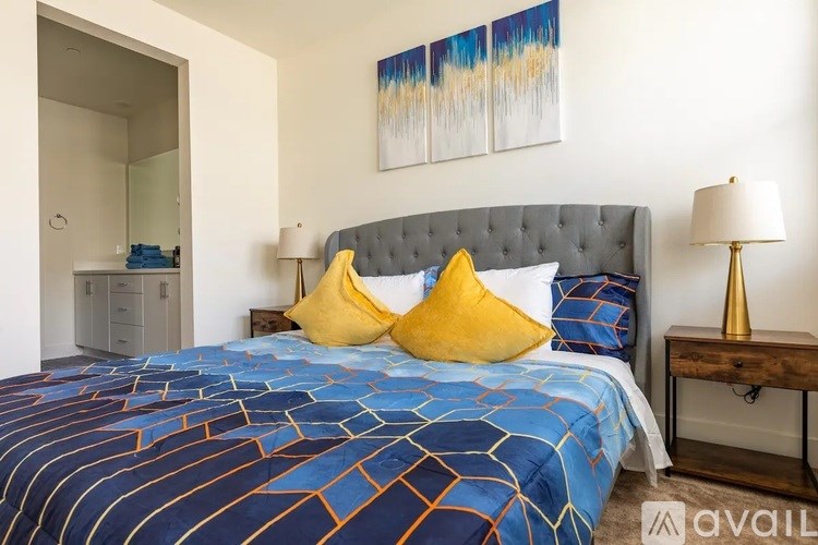 A bed with a blue and orange comforter and two yellow pillows.
