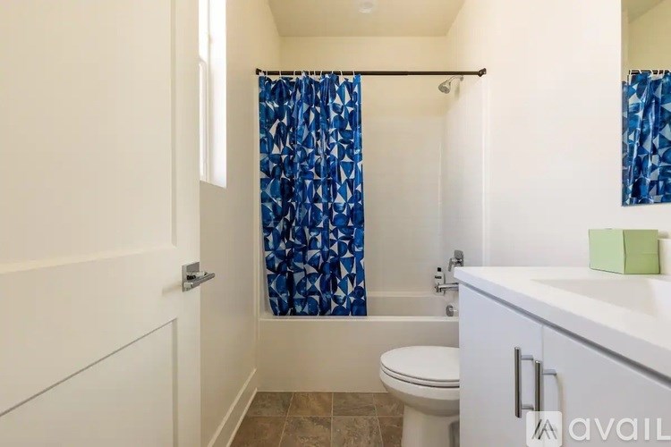 A bathroom with a white toilet, a white sink, and a blue shower curtain.