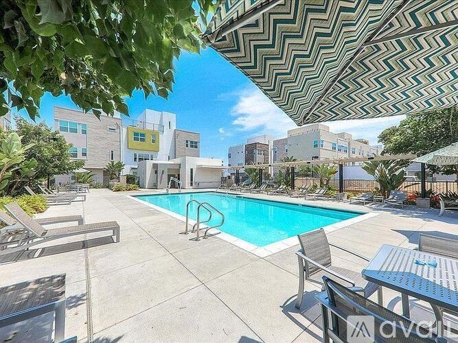 A pool area with sun loungers and a shade structure.