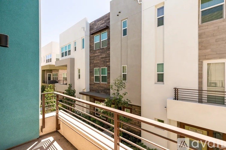 A balcony with a metal railing and a building in the background.