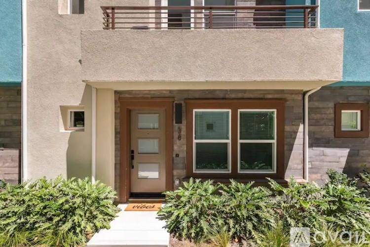 A house with a brown door and glass windows is surrounded by green plants.