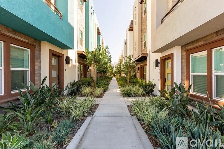 A row of townhouses with a sidewalk in between.