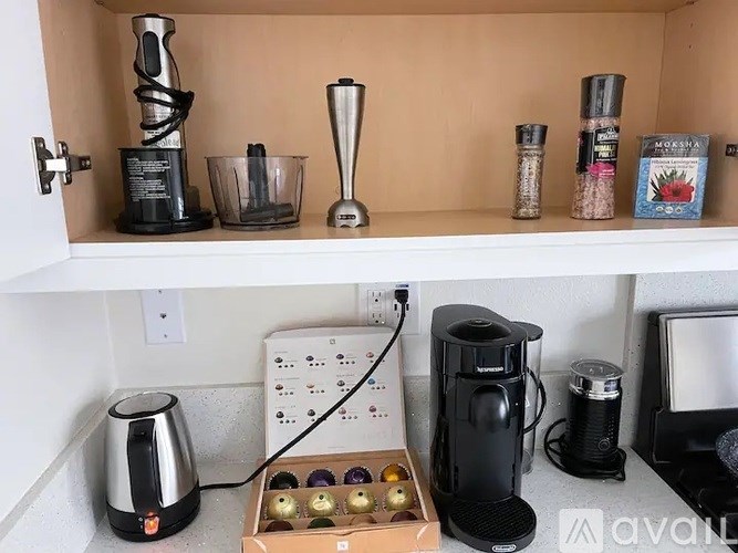 A kitchen counter with a coffee maker, a blender, and a coffee grinder.