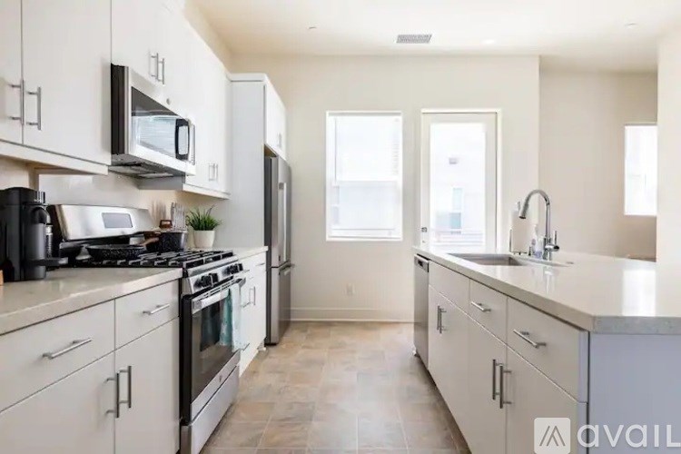 A kitchen with white cabinets and appliances, a stove, and a refrigerator.