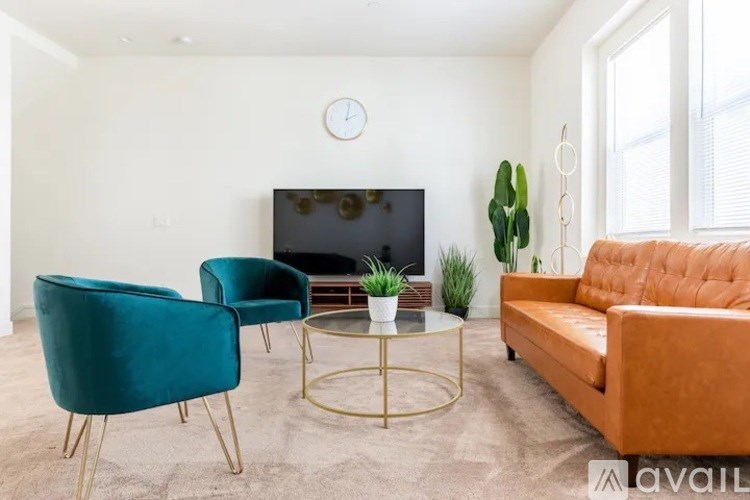 A living room with a sofa, two chairs, a coffee table, and a flat screen TV.