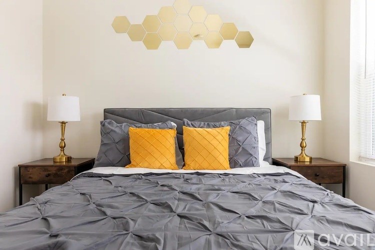 A bed with a grey comforter and two yellow pillows is in the image.