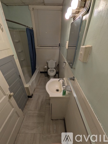 A bathroom with a toilet, sink, and mirror.