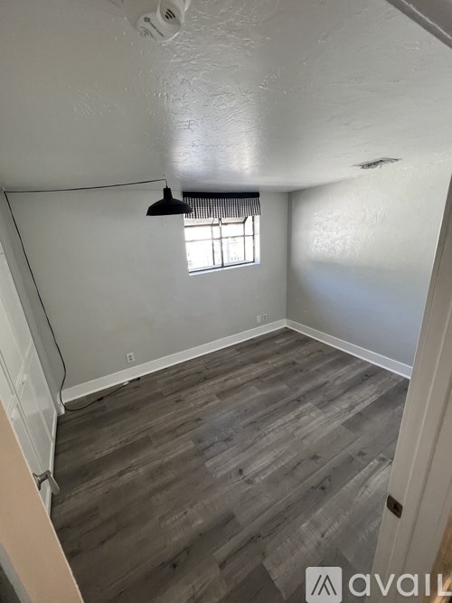 A room with wooden flooring and a window with blinds.