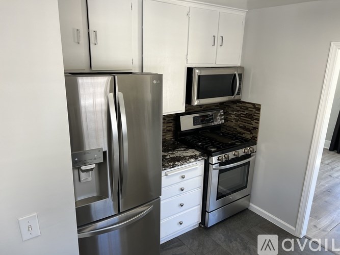 A kitchen with a stainless steel refrigerator, microwave, and oven.
