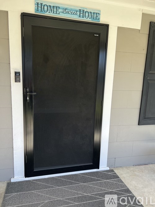 A black door with a glass window and a sign above it that says "HOME SWEET HOME".