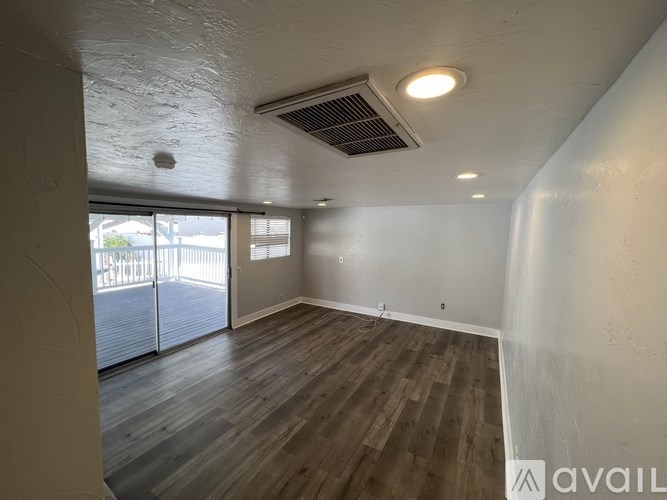 A room with wooden flooring and a sliding glass door leading outside.