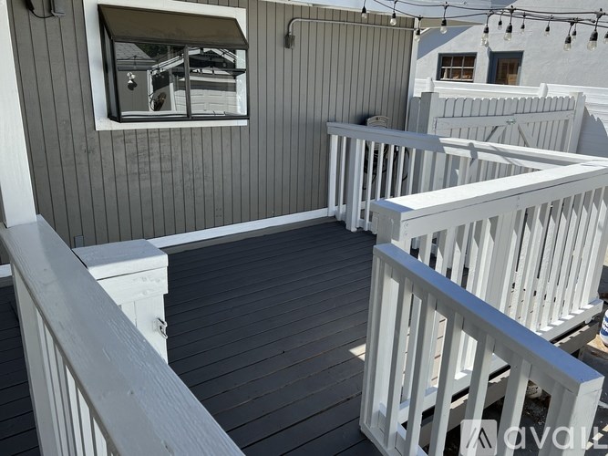 A balcony with white railings and a window overlooking a building.