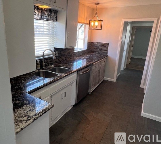 A kitchen with granite countertops and white cabinets.