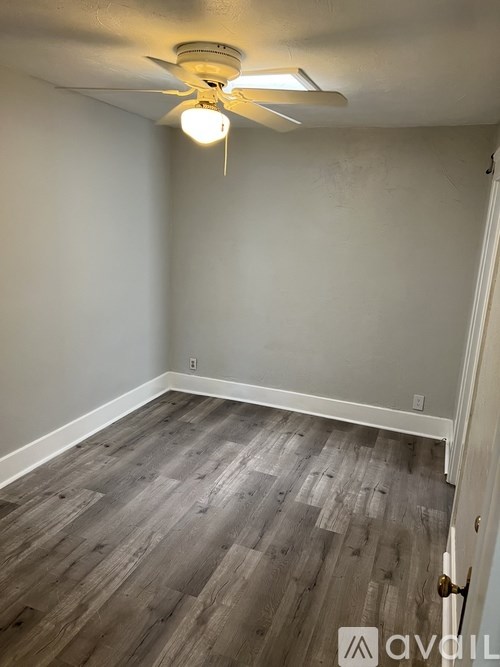 A room with a ceiling fan and wood flooring.