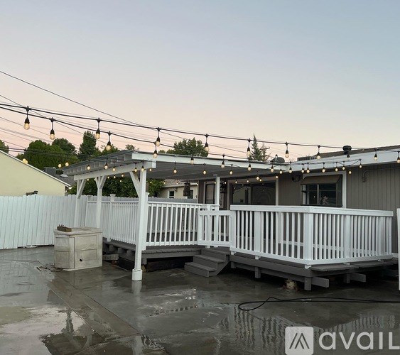 A patio with a white railing and a roof with string lights.