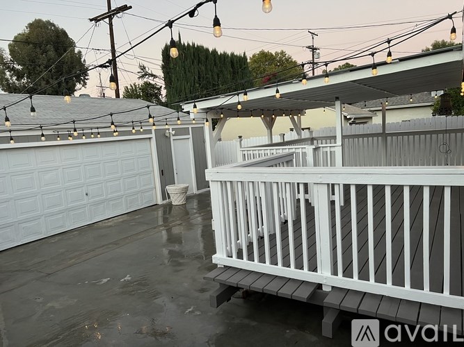 A wet parking lot with a white fence and a garage door.