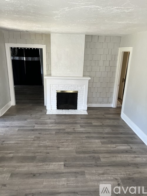 A room with a fireplace and wooden flooring.