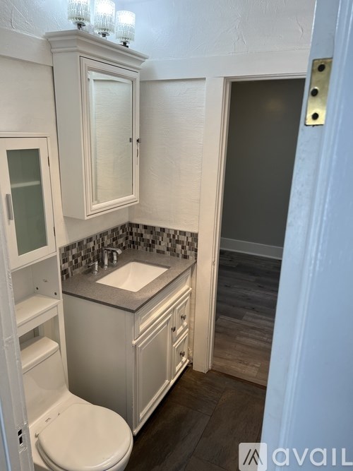 A bathroom with a toilet, sink, and cabinet.