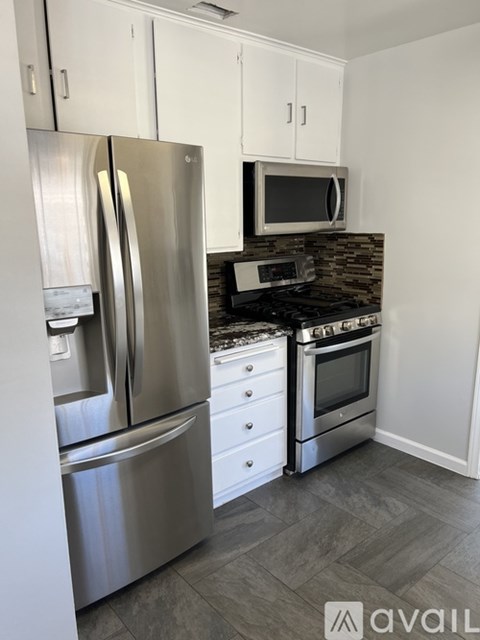 A kitchen with a stainless steel refrigerator and microwave above a stove.
