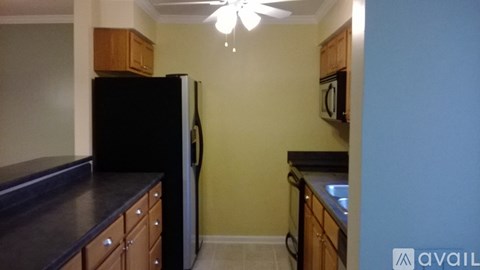A kitchen with a black refrigerator and wooden cabinets.