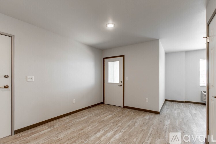 A room with wooden flooring and a door leading to another room.