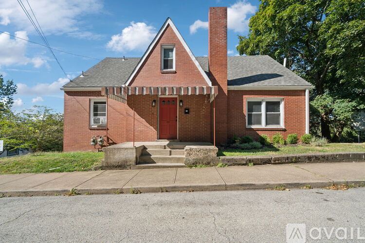 A red brick house with a white door and a brown roof.