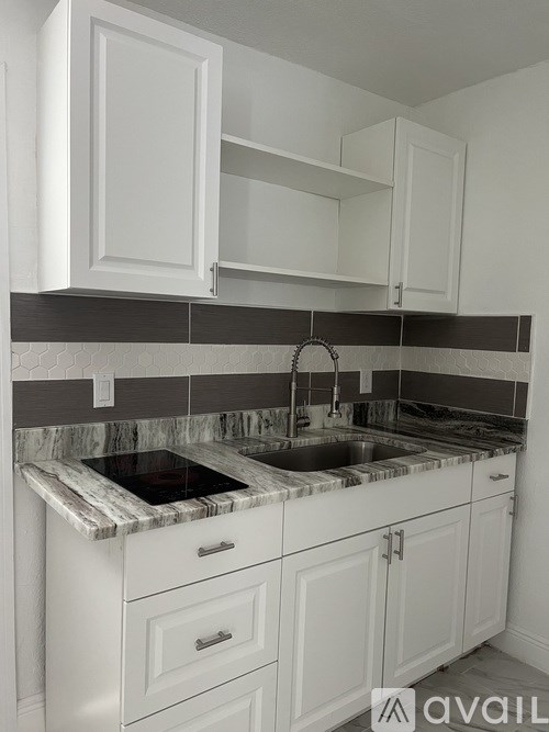 A kitchen with white cabinets and a marble countertop.