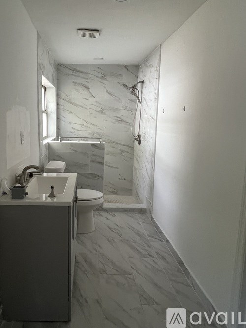 A bathroom with a marble tile floor and walls.