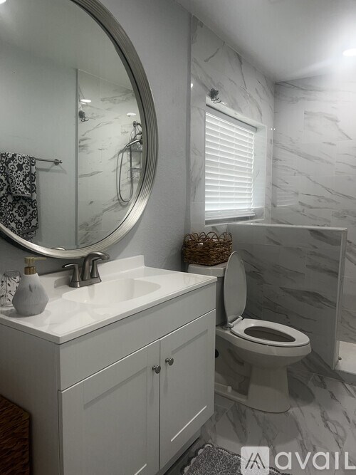 A bathroom with a toilet, sink, and mirror.
