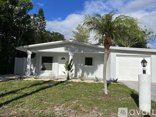 A white house with a palm tree in front.