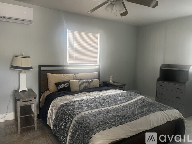 A bedroom with a bed, nightstand, and window.