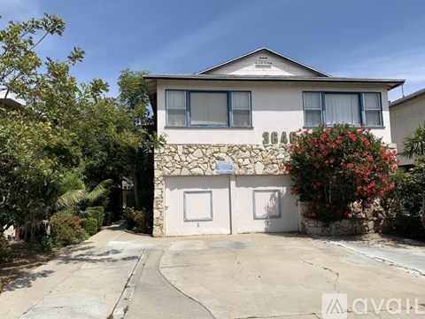 A two-story house with a stone wall and a white door.