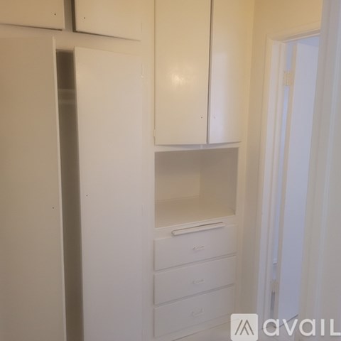 A white kitchen with a refrigerator, cabinets, and drawers.
