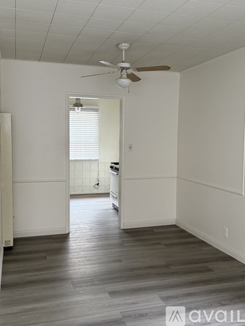 A sidewalk with a bush and trees in front of a house.