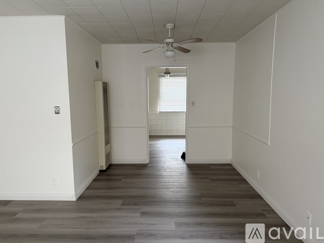 A bedroom with a bed, a dresser, and a window with blinds.