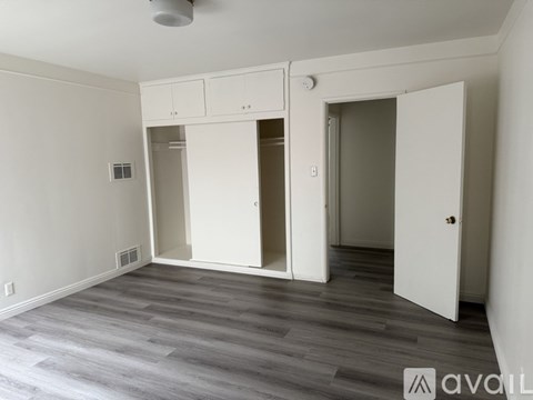 A bedroom with a blue bedspread and a white wall.