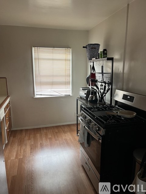 A kitchen with a black stove top oven and wooden flooring.