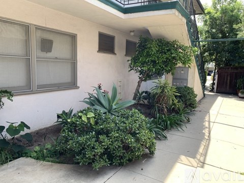 A white house with a green roof and a small garden in front.
