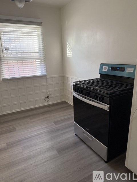 A kitchen with a black oven and wooden flooring.