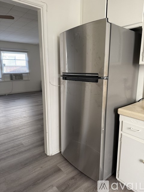 A stainless steel refrigerator is in a kitchen with wood flooring.