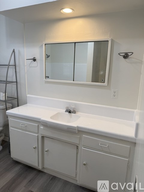 A white bathroom vanity with a sink and mirror.