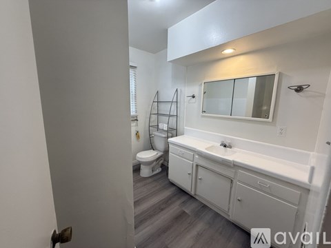 A bathroom with a white toilet, sink, and cabinets.