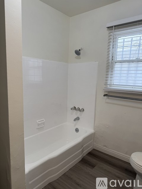 A white bathroom with a tub, toilet and window.