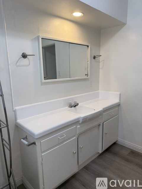 A white bathroom with a sink and mirror.