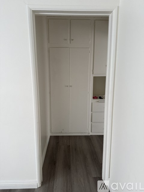 A white closet with drawers and shelves is open to a hallway.
